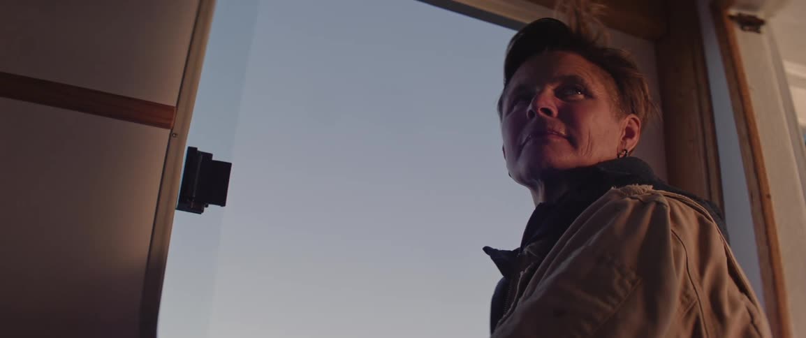 Woman standing by the window watching while in the cabin of a boat