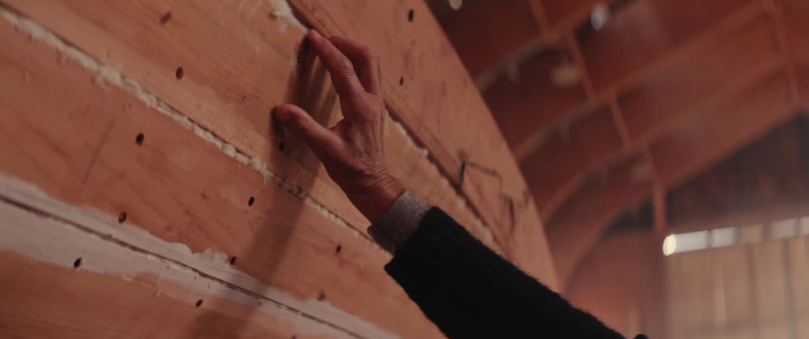 Persons hand passing along the side of a wooden boat