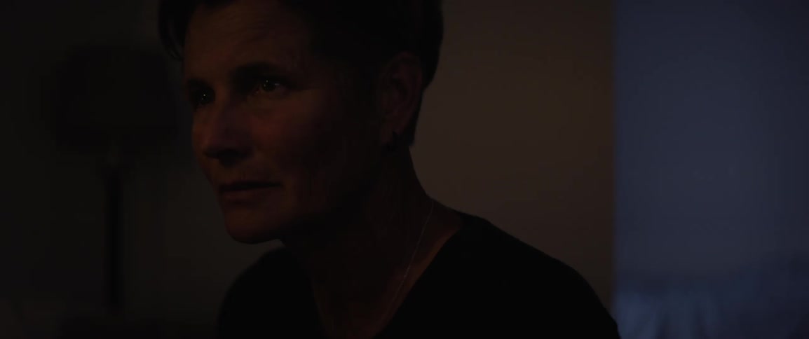 A close up of the face of a woman sitting in a room with moving lights at night