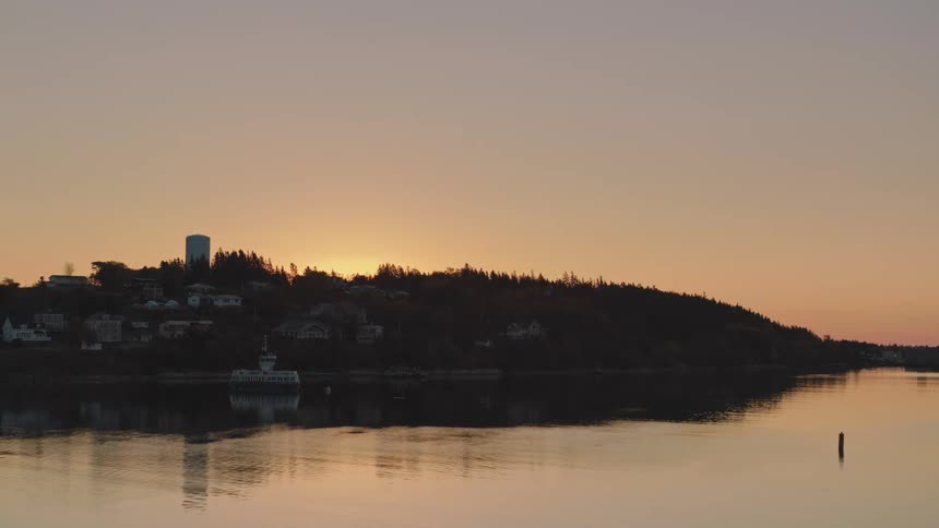 Oceanside houses seen in a calm bay at sunrise