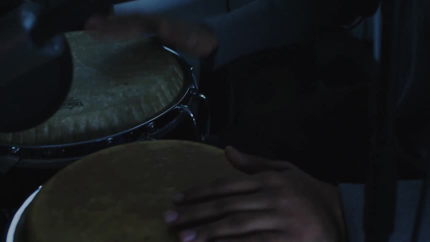 A man is playing the drums by a soundboard