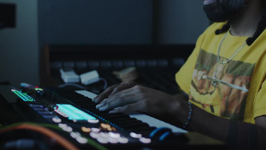 Man in bandana sitting playing an electronic piano