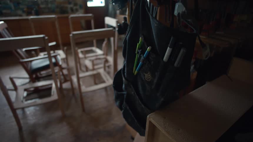Carpenters workshop with chairs under construction and in the foreground a backpack with pens