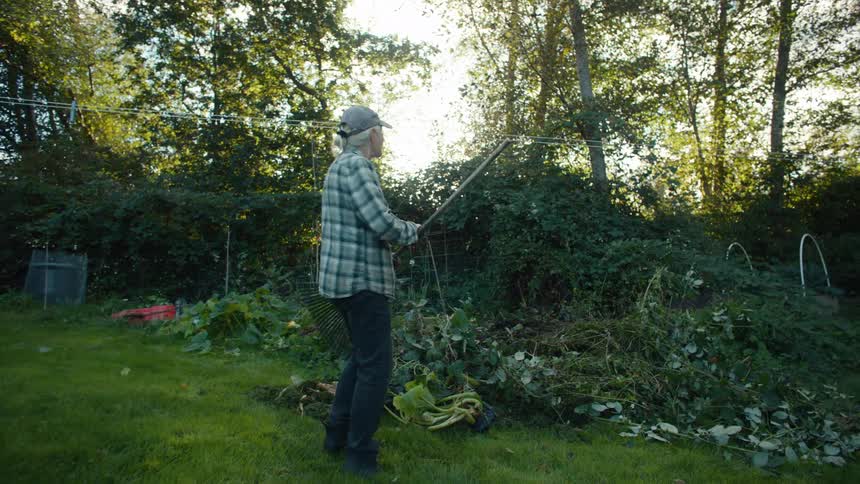 Elderly lady walking through a yard with gardening equipment