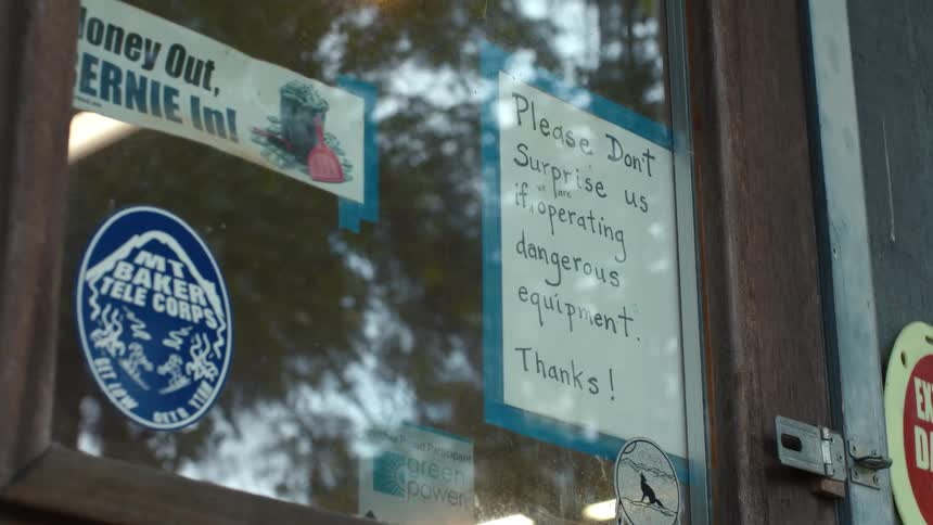 Wooden door glass displays stickers and a handwritten notice