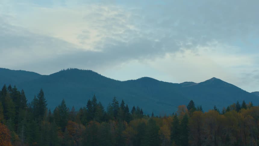 Landscape of mountains covered in trees with a cloudy sky in the background