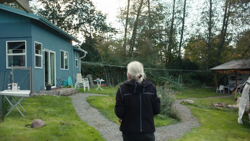 Elderly lady walking in the yard with a bowl of fresh apples