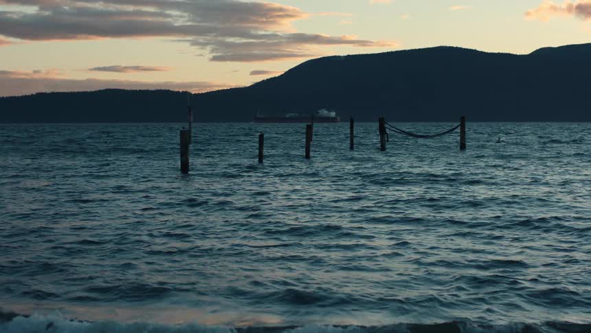 The poles of a long gone pier stick out of the water