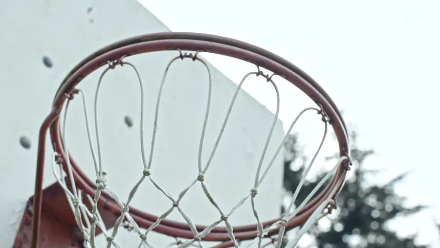 Rusty basketball hoop with worn net attached to a white backboard