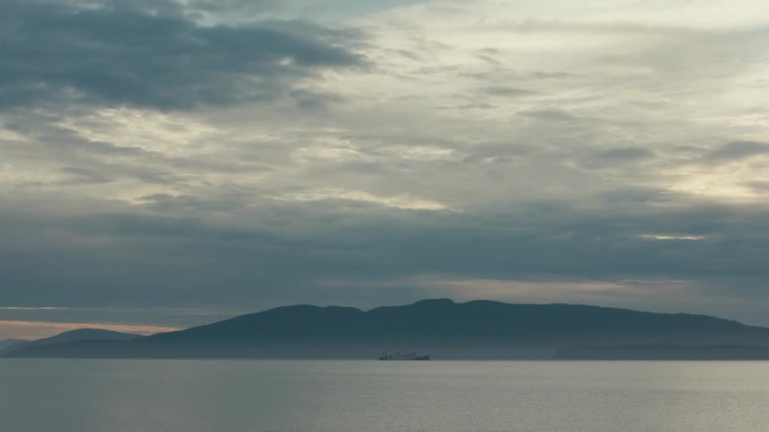 Ocean landscape with silhouette of a boat on a mountain on the horizon
