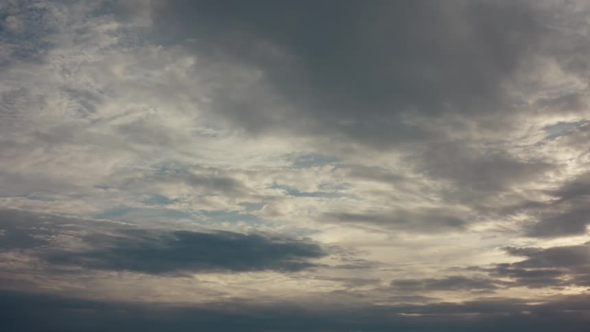 Sky covered by clouds with light and dark tones and a bird flying to the left