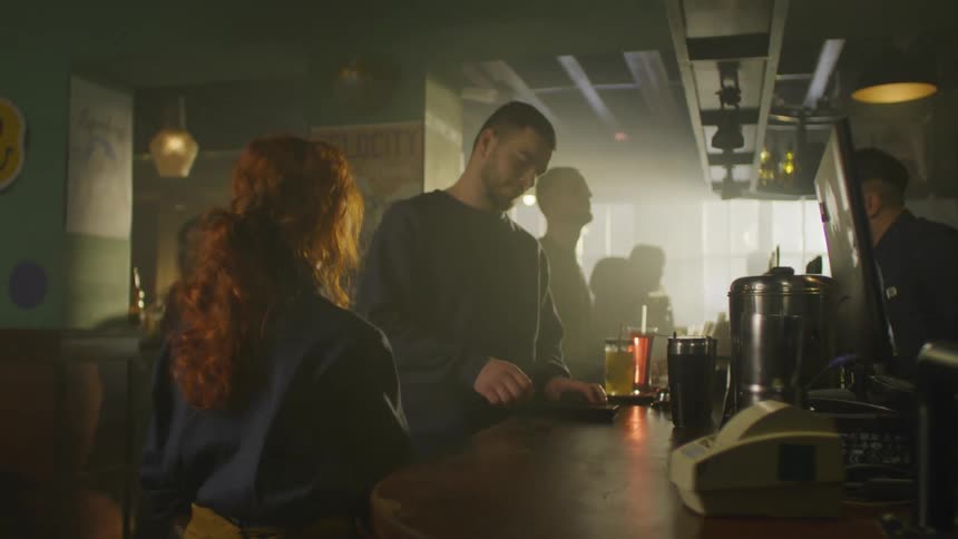 Waitress taking a bar receipt from a bill and handing it to a man