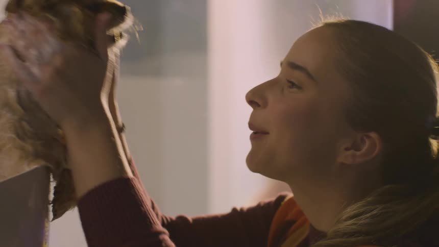 A blondehaired woman lathers a small dog in a bathtub giving it eskimo kisses