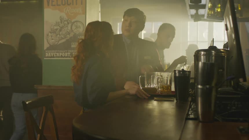 Bar attendant working at a bar carrying beer to a counter