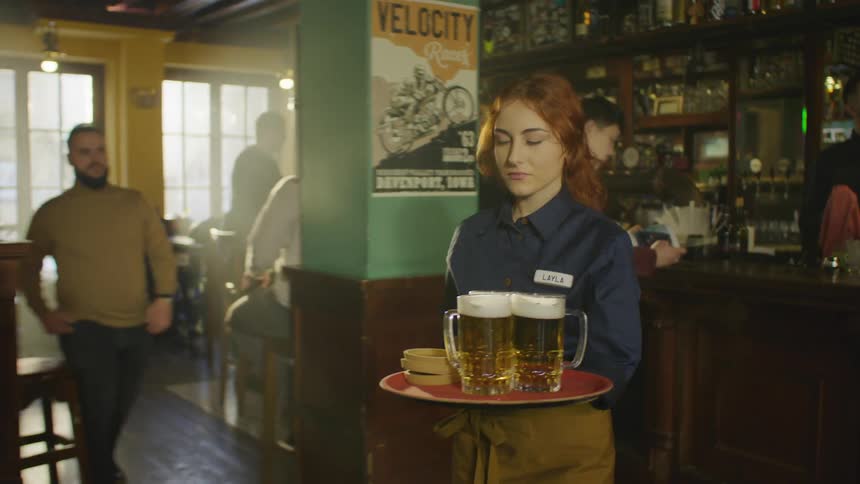 Waitress carrying three beers across the bar