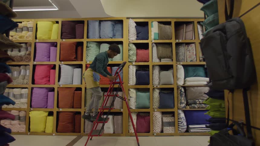 Young man in a store putting an object away on a shelf