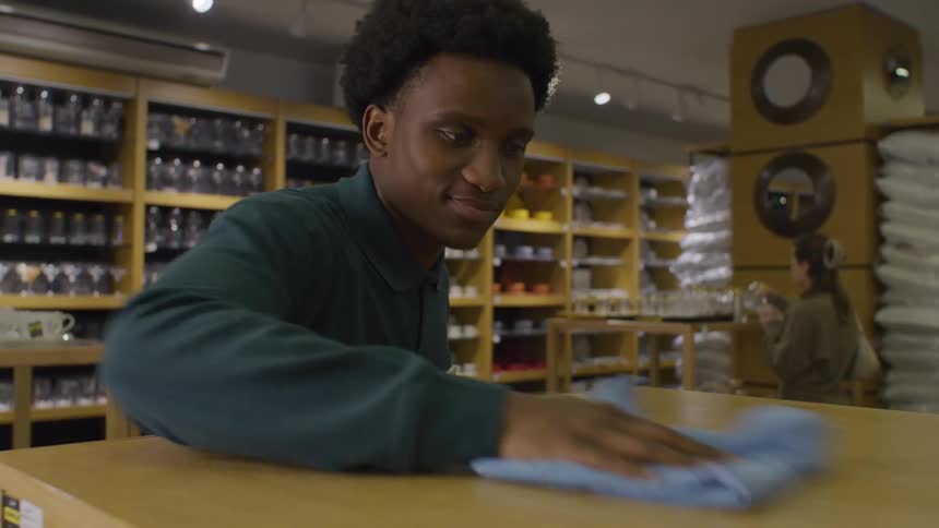 The face of a happy young man cleaning a wooden countertop in an establishment