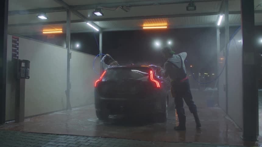 Black suv being washed by two people with water jets