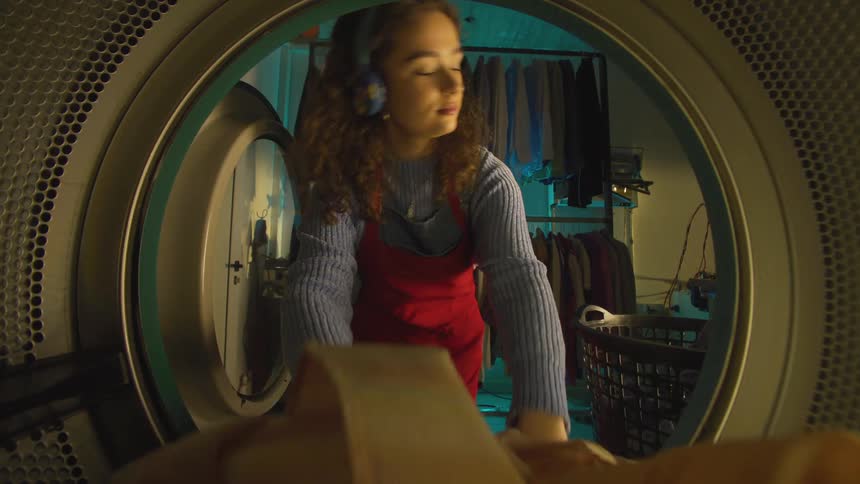 Woman in red apron putting clothes into a washing machine