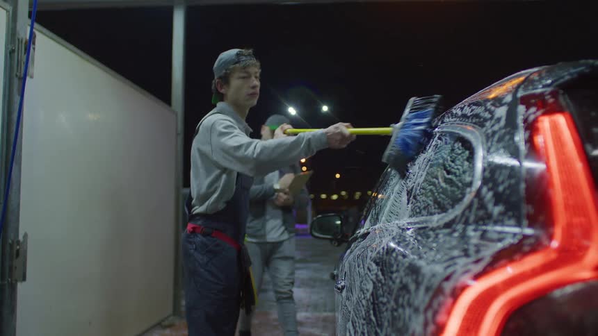 A man is approached while he cleans a car at the car wash