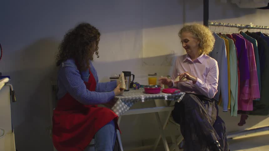 A couple of employees eat lunch at a small table in the back of a laundry