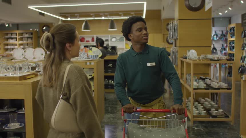 Clerk walking with a shopping cart through a store