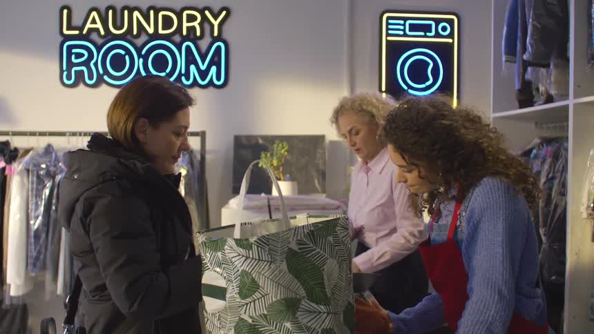 Employees in a laundry room receive clothes and write a receipt for a customer