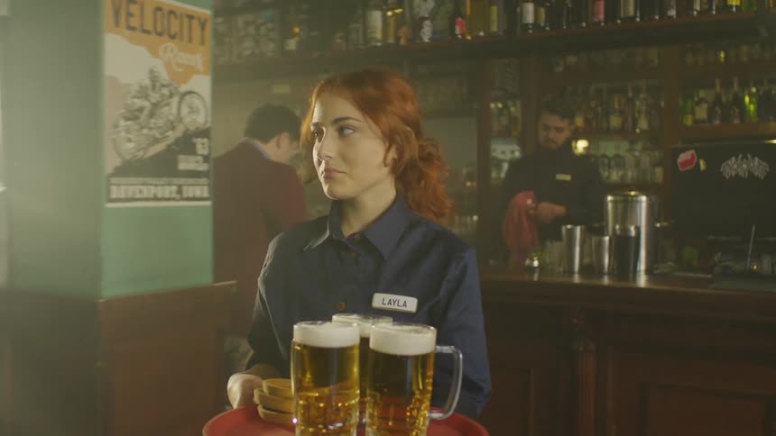Female waitress grabbing two beers and moving around the bar