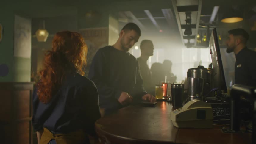 Bar attendant taking the bill and handing it to a man