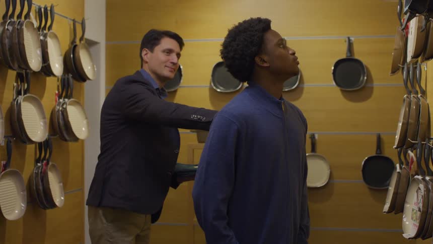 An employee approaches a customer and shakes his hand