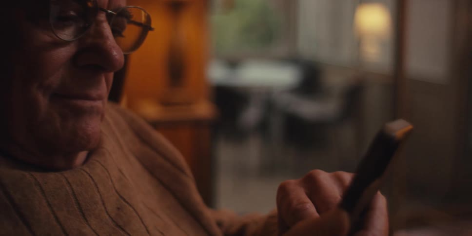 Elderly man sitting interacting with a smartphone