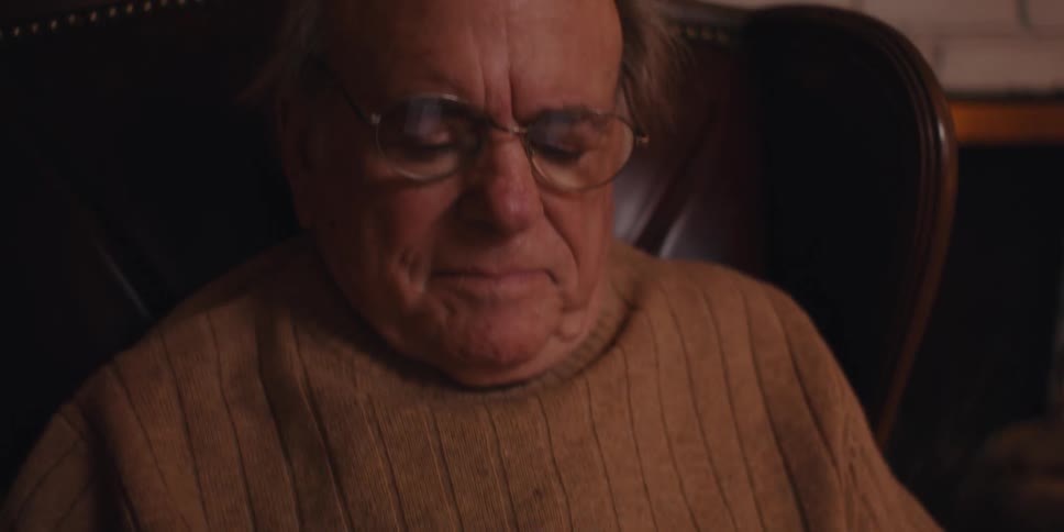 Elderly man sitting in an armchair using his cell phone