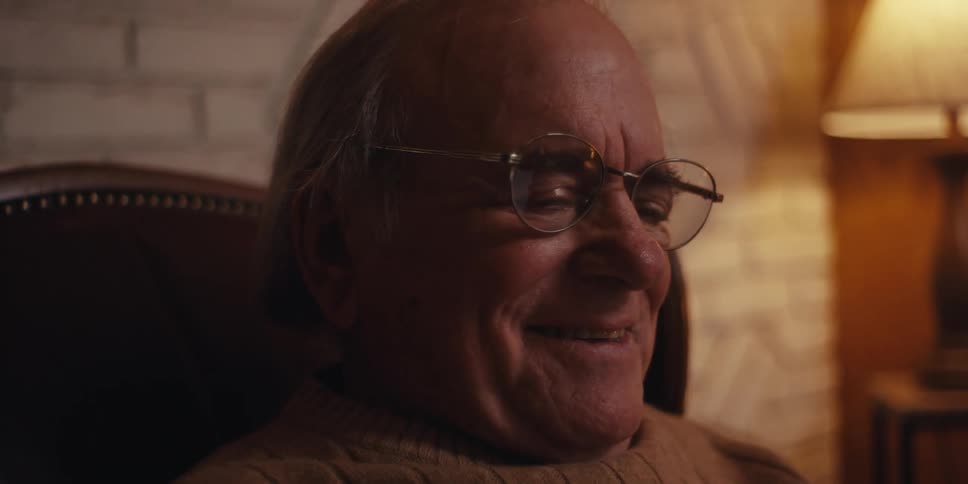 Elderly man sitting in an armchair in the living room and interacting with a smartphone