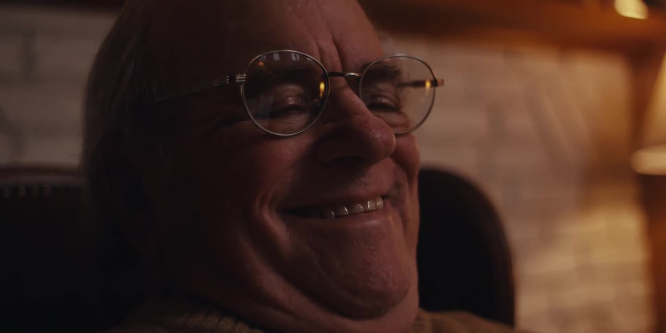 Portrait of an elderly man sitting in an armchair laughing while interacting with a smartphone