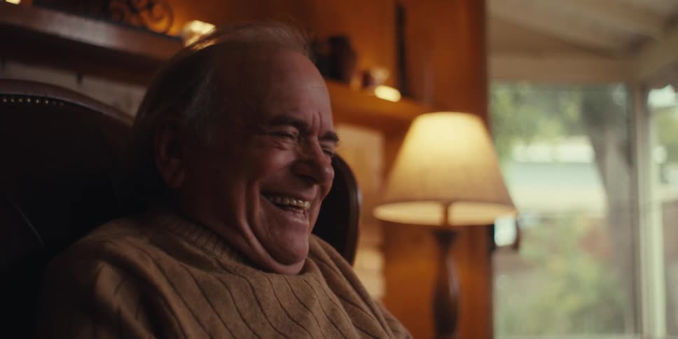 Elderly man laughing out loud while holding a smartphone