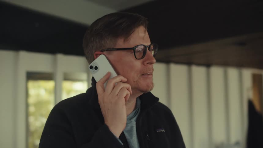 Man wearing glasses and a black jacket talks on the smartphone