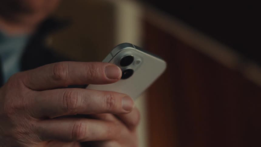 A hand holding a silver smartphone focusing on the phones camera module with its two lenses