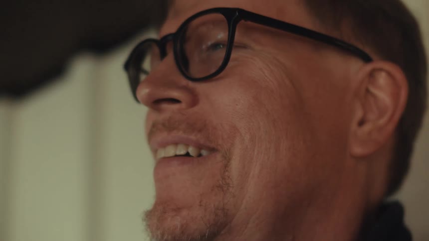 Man looks up from what he is doing and after thinking for a moment smiles