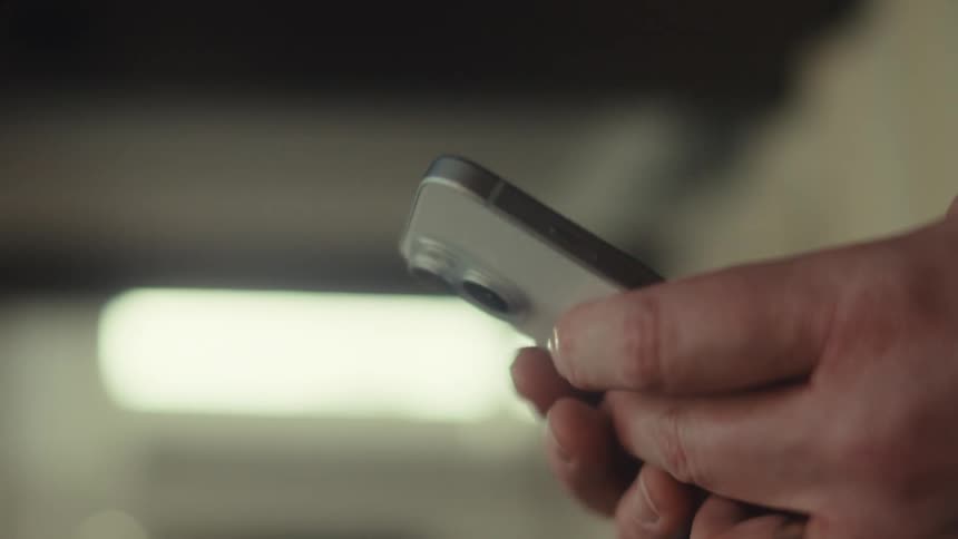 Man with sunglasses and a black jacket uses a silver iphone