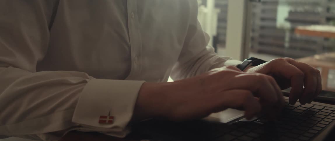 Man types on a laptop while a calculator sits on the table nearby