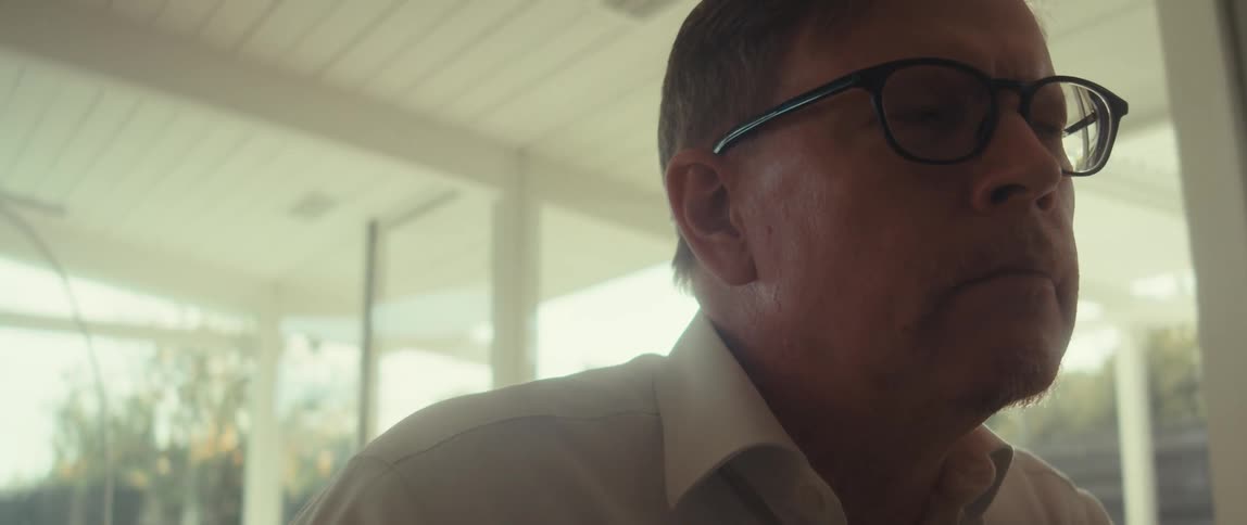 Man sitting indoors on a sunny day looks up to stare in thought