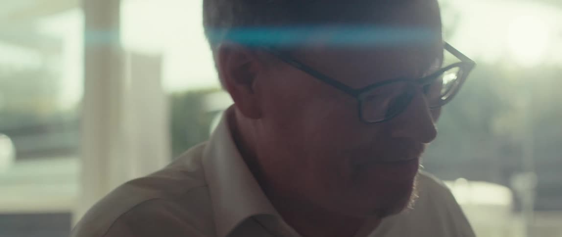 Man wearing glasses and a white shirt is partially illuminated by the sun