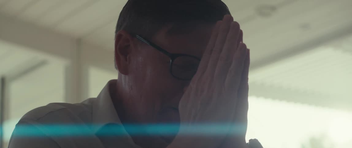 Man working indoors shakes his head and puts his hands together on a sunny day