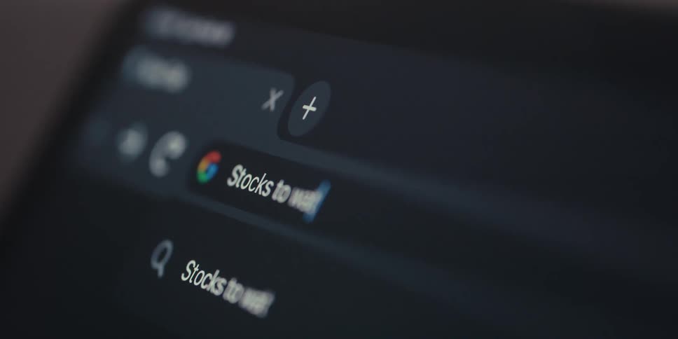 On a laptop a user types stocks to watch into google chrome transitioning to a search results page