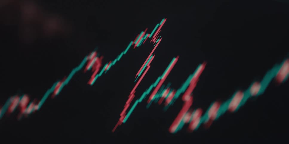 A computer screen displaying a stock market candlestick chart with fluctuating red and green lines indicating market trends