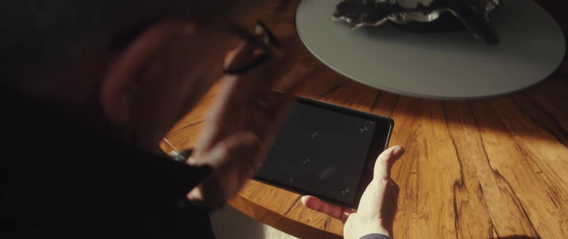 A man views a tablet with tracking markers on the screen while sitting at a wooden table