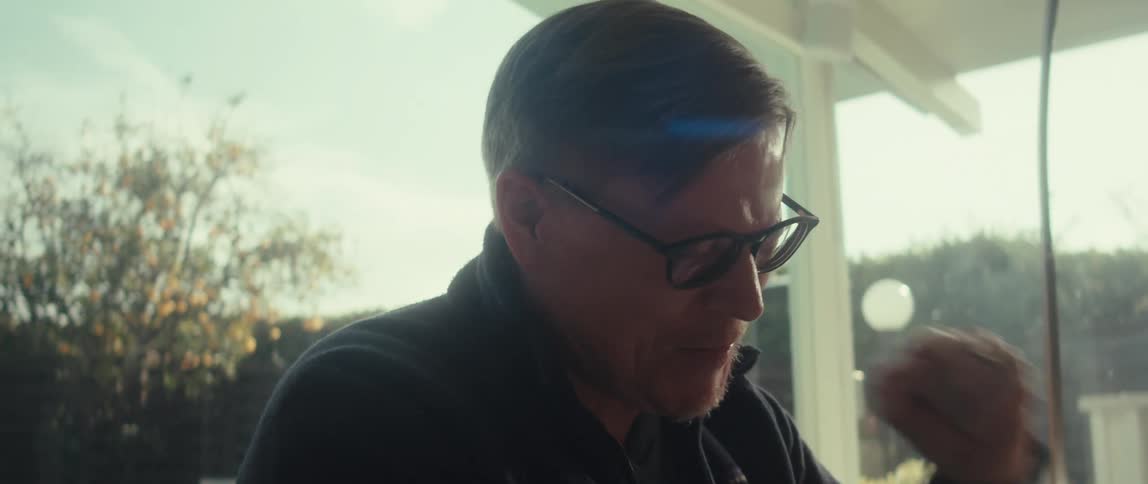 A man with glasses enthusiastically clenches his fist while looking at a tablet