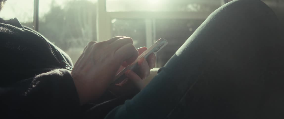 A person uses a smartphone near a brightly lit window