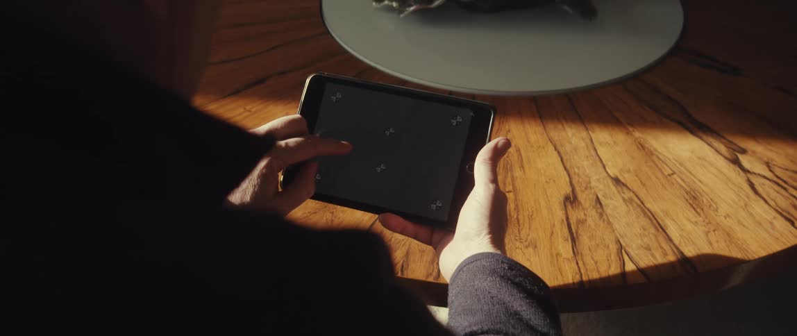 A person sitting at a table scrolls and taps on a tablet screen with motion tracking markers