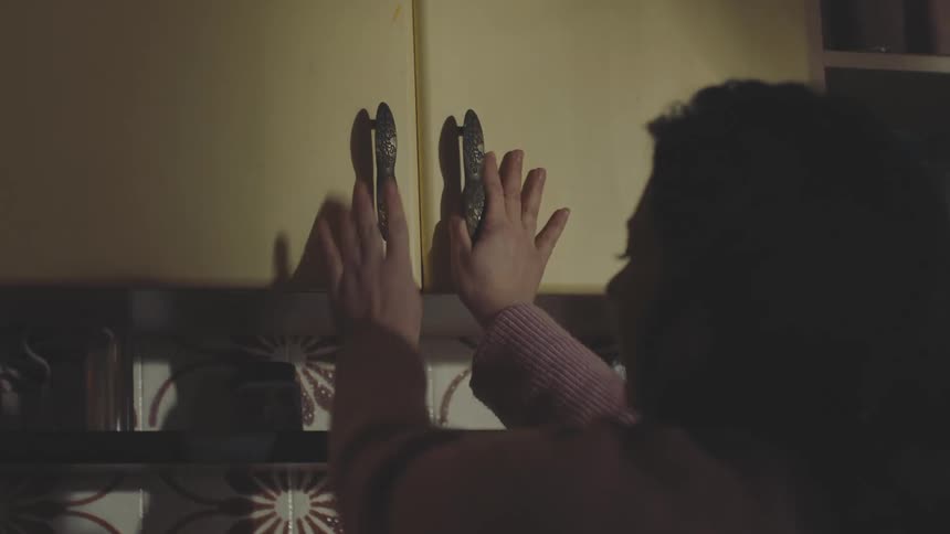 Woman putting away a jar of cookies in the cupboard